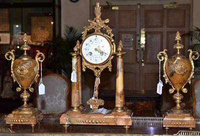 Lot 479 - A gilt metal mounted striking mantel clock with urn-shaped garniture, retailed by A.Bony, Clermont