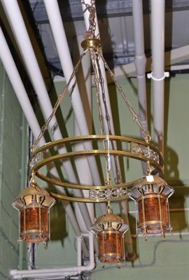 Lot 668 - Brass circular light fitting with three amber tinted suspended lanterns