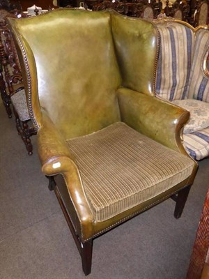 Lot 838 - Olive leather wing armchair with corduroy squab and bolster cushion