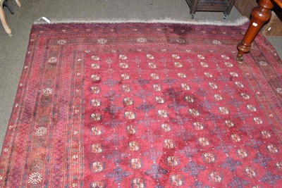 Lot 936 - An Afghan red ground carpet, decorated with canted square medallions within a broad border of...