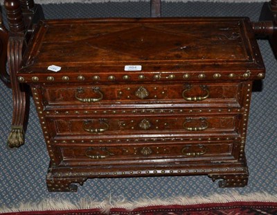 Lot 984 - A Spanish walnut and brass-studded miniature chest of three drawers with brass drop handles, raised