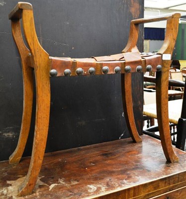 Lot 1539 - An Arts & Crafts oak music seat, the rectangular seat with interwoven leather straps, brass...