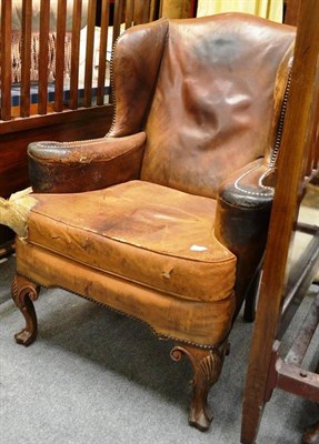 Lot 1573 - Three Georgian style wingback armchairs upholstered in brown close nailed leather