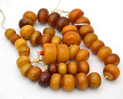 Lot 6 - Two strands of amber beads, and one loose bead, of orangey-yellow colour