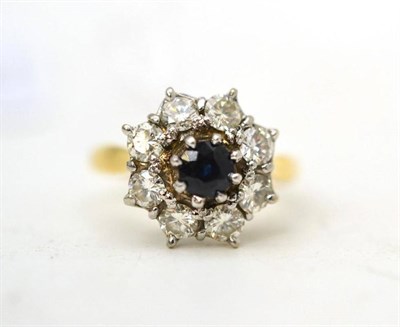 Lot 11 - An 18ct gold sapphire and diamond cluster ring, the round cut sapphire within a border of round...