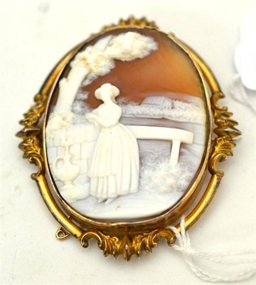 Lot 18 - A Victorian cameo brooch, depicting a maiden collecting water beneath a tree, in a fancy frame,...