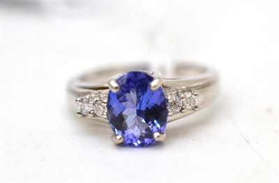 Lot 21 - An 18ct white gold tanzanite and diamond ring, the oval mixed cut tanzanite with two round...