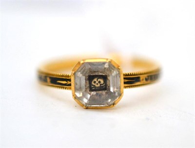 Lot 31 - A mourning ring, with a skull and crossbones under an octagonal rock crystal on a band enamelled in