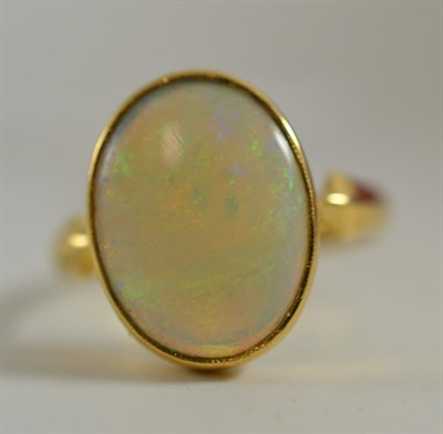 Lot 129 - An opal ring, the oval cabochon opal in a yellow rubbed over mount, to shaped shoulders, on a plain