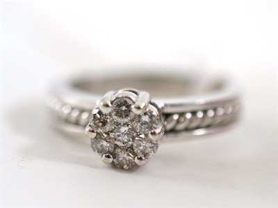 Lot 149 - A diamond cluster ring, seven round brilliant cut diamonds in white claws on rope twist...