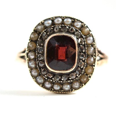 Lot 301 - A garnet, diamond and seed pearl cluster ring, a cushion cut garnet  in a yellow rubbed over...