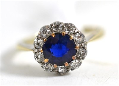 Lot 319 - A sapphire and diamond cluster ring, the round cut sapphire in a border of old cut diamonds, in...