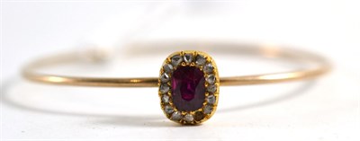 Lot 441 - A ruby and diamond bangle, the cushion cut ruby within a border of rose cut diamonds on a wire...