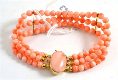 Lot 447 - Coral bracelet, three rows of round beads with spacers at intervals, strung to an oval cabochon...