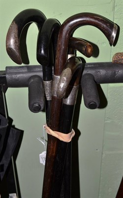 Lot 490 - Five ebonised walking sticks, some with silver ferrules