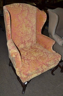 Lot 736 - A George II style wing chair on walnut carved legs, joined by a H stretcher