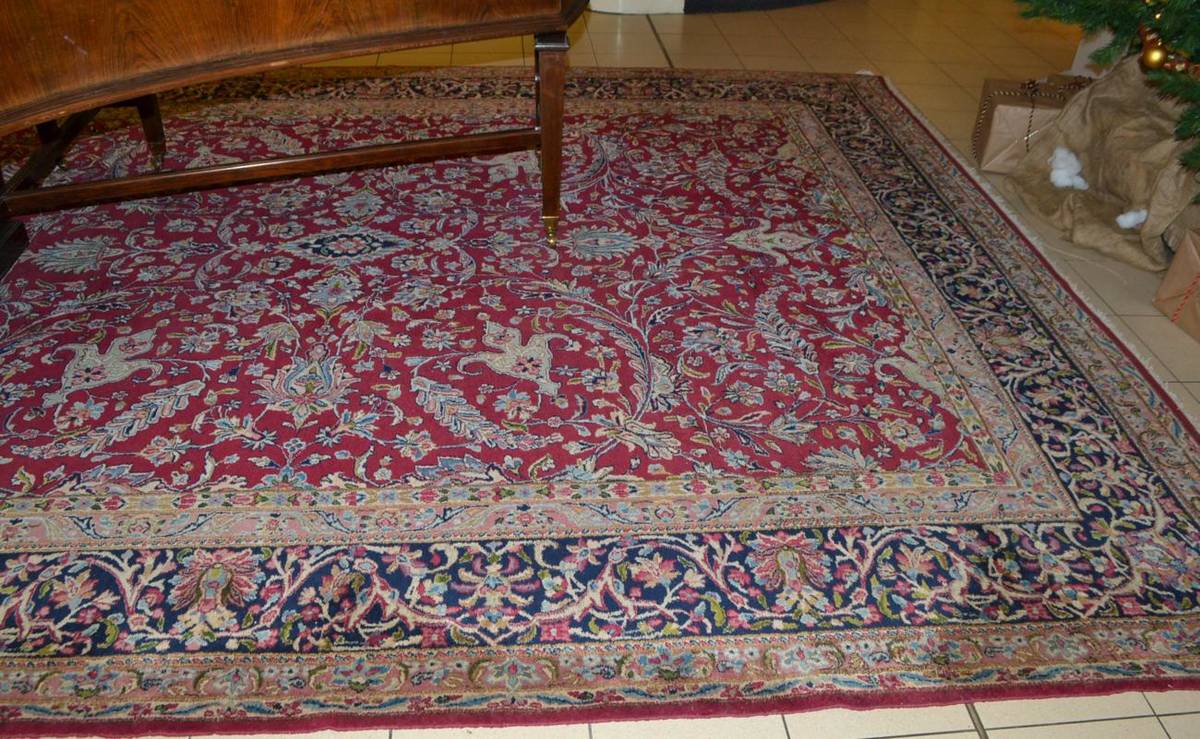 Lot 1492 - Kirman carpet, South East Persia, the raspberry field of scrolling vines around a floral...