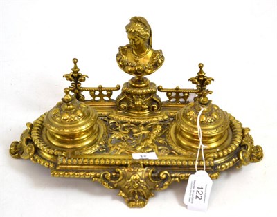 Lot 122 - A cast and pierced brass inkstand, circa 1870, with a bust portrait flanked by two ink pots on...