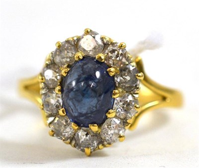 Lot 242 - A cluster ring, the blue oval cabochon within a border of old cut diamonds in yellow claw settings