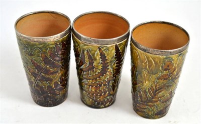 Lot 523 - Three Doulton stoneware beakers with silver rims