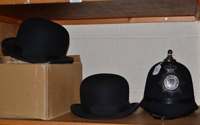 Lot 561 - Two bowler hats and a police helmet