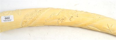 Lot 660 - An ivory tusk, circa 1900, carved with animals and foliage, 68cm wide