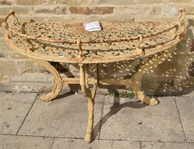 Lot 1358 - A Victorian cast iron demi-lune table, with wrythen gallery, strapwork top, leaf sheathed...