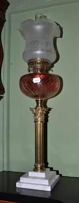 Lot 1390 - Brass oil lamp with cranberry glass reservoir and brass column support, 77cm high