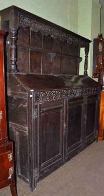 Lot 1403 - An 18th century large oak dresser with two hinged sloping doors to the top and rack with carved...