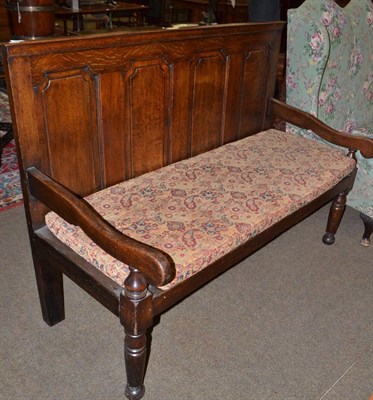 Lot 1481 - George III oak settle with fielded panel back support and squat cushion