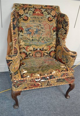 Lot 1875 - A wing back armchair, in 18th century style, covered in needlework fabric, with curved armrests and