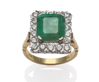 Lot 33 - An emerald and diamond cluster ring, an emerald-cut emerald in a white claw setting, within a...