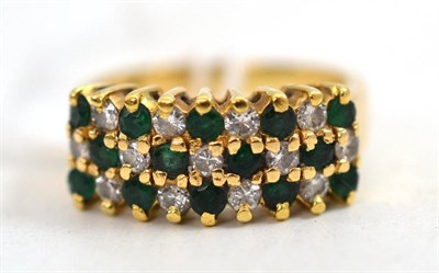 Lot 45 - A diamond and emerald ring, the round cut stones alternate across three rows, creating a...