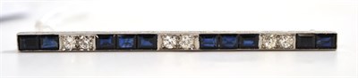 Lot 60 - A sapphire and diamond bar brooch, series of blue step cut sapphires alternate with pairs of...