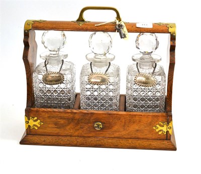 Lot 113 - Brass bound oak tantalus, 19th century, containing three hob-nail cut decanters and stoppers,...