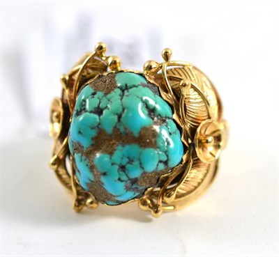 Lot 254 - A turquoise set ring, the tumbled veined turquoise in a floral and foliate decorated mount,...