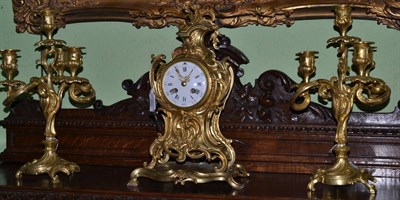 Lot 566 - A gilt metal striking mantel clock with garniture, circa 1900, scroll decorated case, 4-inch enamel