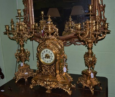 Lot 589 - An ormolu striking mantel clock with garniture, circa 1890, the elaborate case surmounted by an urn