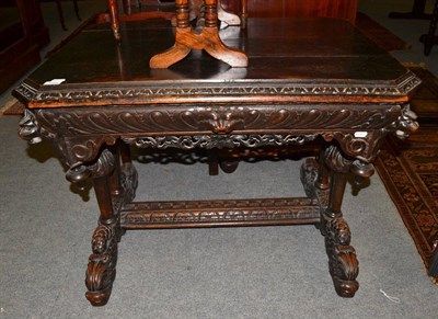 Lot 1280 - A Victorian dark carved oak centre table, carved with mask heads on four column supports and...