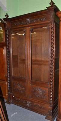 Lot 1405 - A 19th century oak armoire enclosed by two glazed and panelled doors and spiral turned columns