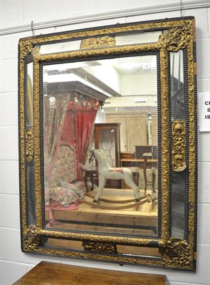 Lot 1536 - A 19th century ebonised and brass repoussé decorated marginal mirror, 139cm by 107cm