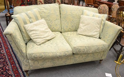 Lot 1568 - A modern two-seater sofa upholstered in light green and floral brocade