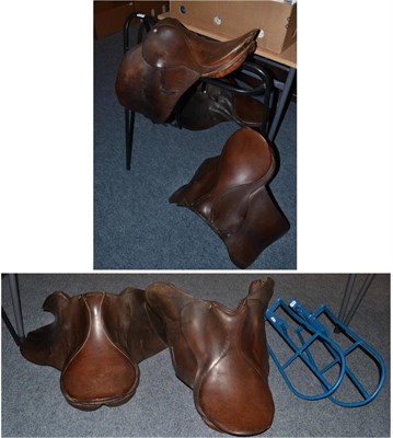 Lot 1602 - Black saddle stand, two wall mounted stands and four brown leather saddles