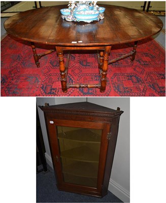 Lot 1642 - An oak eight seater drop-leaf table on turned supports and a George III corner cupboard