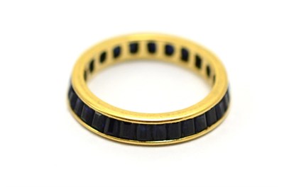 Lot 545 - # A synthetic sapphire eternity ring in a yellow channel setting, finger size N