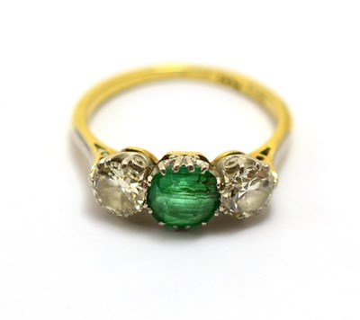 Lot 550 - An early 20th century emerald and diamond three stone ring, the mixed cut emerald between an...