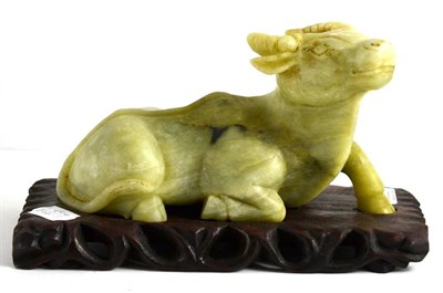 Lot 647 - A Chinese carved jade model of a recumbent buffalo, 20cm long, on a hardwood stand