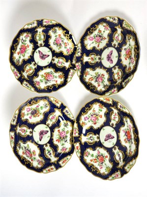 Lot 421 - A set of four Worcester style porcelain plates painted with flowers on a blue scale ground,...