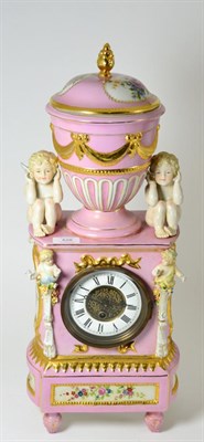 Lot 428 - A porcelain pink ground mantel timepiece, 20th century, surmounted by an urn finial and cover,...