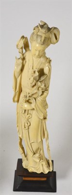 Lot 759 - A Chinese ivory figure of a maiden, 19th century, standing wearing flowing robes holding a lily...